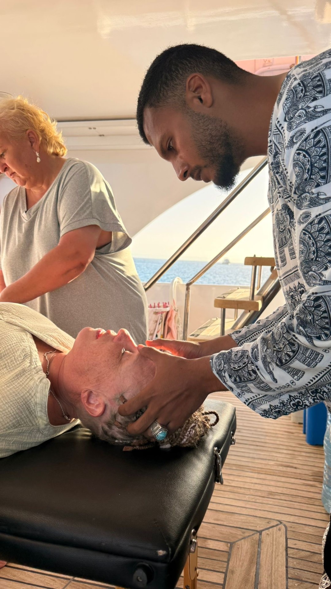 A guest receiving a gentle healing treatment on the boat deck at sunset