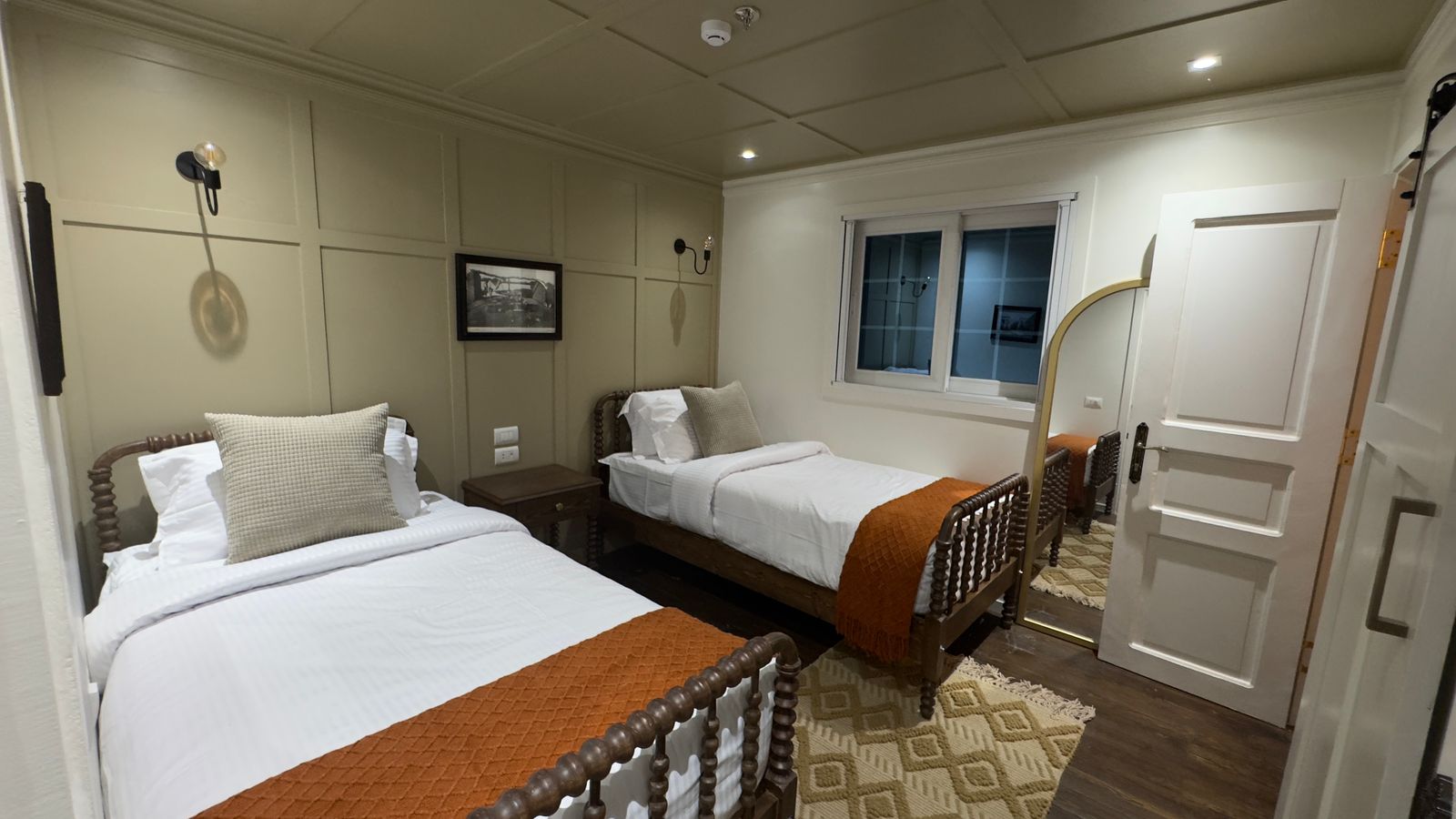 Twin cabin aboard the dahabiya with two beds and warm wood details